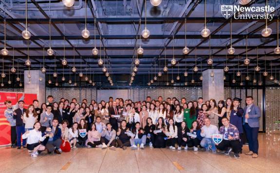 Group shot of China-based NUBS alumni in ballroom with hanging lights